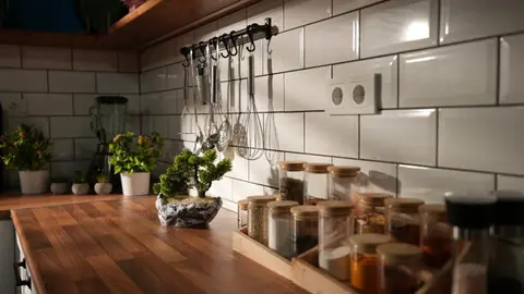 Ahşap tezgâh üzerinde baharat kavanozları ve asılı mutfak gereçleri